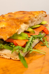 Focaccia croccante romana ripiena di salmone affumicato, avocado, rucola e formaggio servita in un pub