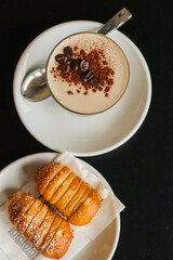Crema di caffè fredda guarnita con cacao e chicchi di caffè e due dolci ripieni di crema al pistacchio serviti come colazione servita in un bar elegante