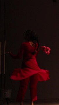 A kathak dancer in simple red dress doing chakkar, chakras or spin practice in the studio with dark lightings, kathak spins