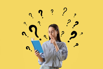Thoughtful young woman reading book on yellow background