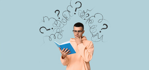 Pondering young man reading book on blue background