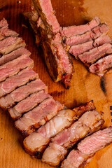 Bistecca di carne al sangue cotta alla brace, scaloppata e servita su un tagliere di legno in una braceria