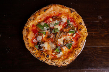 Pizza tradizionale napoletana con sugo di pomodoro, mozzarella, basilico, melanzane fritte e scagli di parmigiano