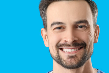 Obraz premium Smiling male dentist with healthy teeth on blue background, closeup