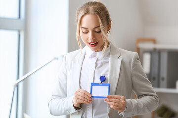 Young businesswoman with blank badge in office