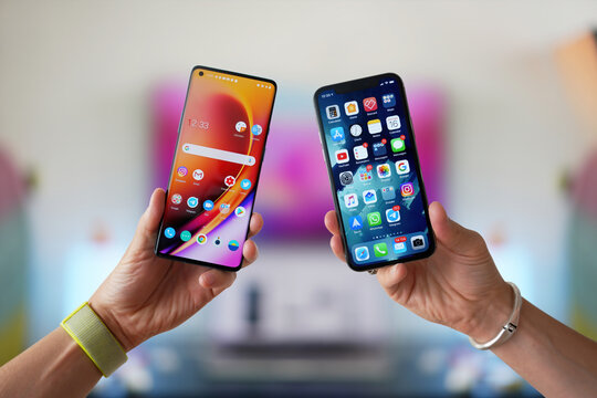iPhone vs Android. A man holds two smartphones side by side in his hands. Comparison, analysis or comparison of two new smartphones on different operating systems.