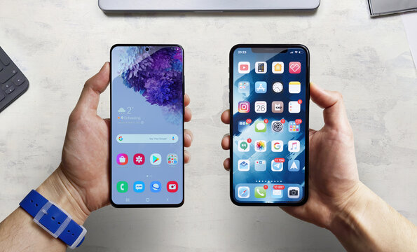 iPhone vs Android. A man holds two smartphones side by side in his hands. Comparison, analysis or comparison of two new smartphones on different operating systems.