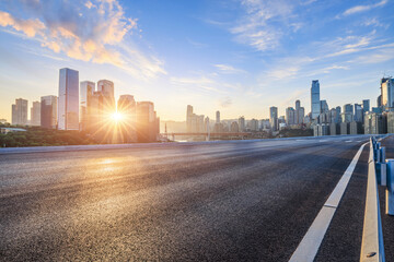 Asphalt road and city skyline with modern buildings in Chongqing at sunrise.