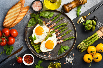 Delicious Breakfast: A plate with fried asparagus, bacon and fried eggs.
