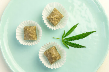 Colorful candy with cannabis leaves. Sweets with CBD oil. Marijuana leaf on blue background. narcotic ingredient in food for relaxation. Top view, flat lay.