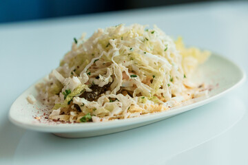 Salad with cabbage cucumber egg onion and mayonnaise on a white saucer on a white background