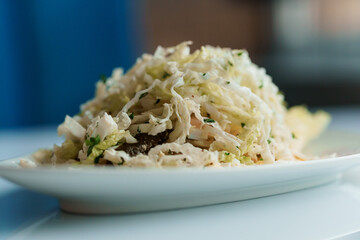 Salad with cabbage cucumber egg onion and mayonnaise on a white saucer on a white background
