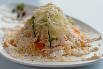 Salad with cabbage cucumber egg onion and mayonnaise on a white saucer on a white background