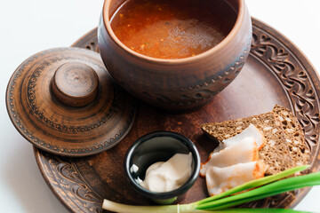 Red borscht in a pan with lard and green onions
