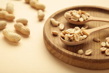 Fresh healthy peanuts in bowl and spoon on beige background.