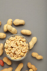Roasted peanuts on bowl on grey background. Vertical photo