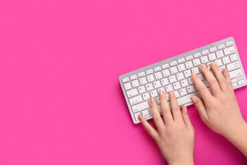 Female hands typing on keyboard on pink background