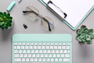 Keyboard, eyeglasses and cactus on grey background. Top view