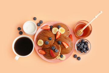 Tasty pancakes with blueberries and banana on orange background