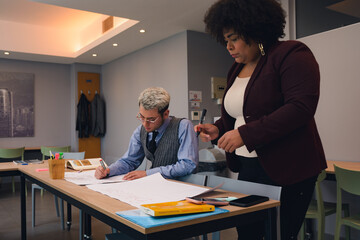 An Afro Woman and a young Man are planning activities with a piece of paper on table.