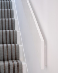 Minimalist, white painted MDF handrail banister with clean lines, at side of staircase in Edwardian...
