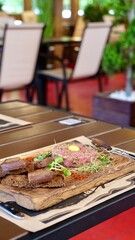 Food in a restaurant with meat pork, steak, sausages, tartar on a table with drinks on a summer terrace