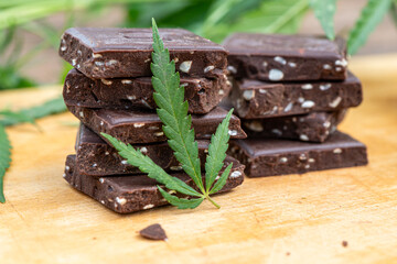 Marijuana leaf edible cannabis with CBD and cereal crunchy food multigrain chocolate, hemp, and oil extracted canabis on brown wooden background.