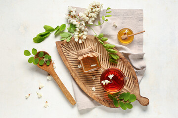 Jar of sweet honey with acacia flowers and glass cup of tea on white background