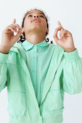 Happy young boy celebrating success in a green jacket with hands raised and big smile