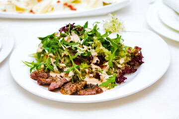 A plate of food with a sauce on it. The sauce is green and the food is meat and lettuce