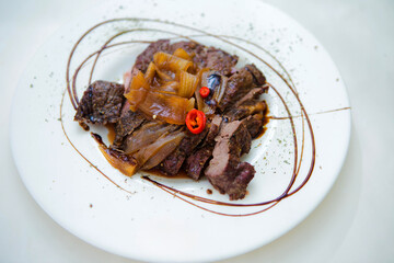 A plate of meat with a sauce and a green leaf on top