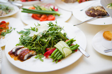 A plate of food with a salad and a piece of meat. The plate is on a table with other plates of food