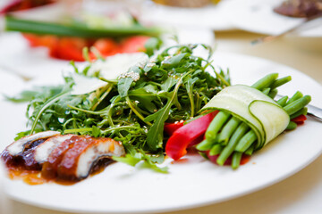 A plate of food with a variety of vegetables and a piece of meat. The vegetables include broccoli, cucumbers, and peppers.