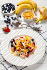 fresh berries, banana with corn flakes and yogurt