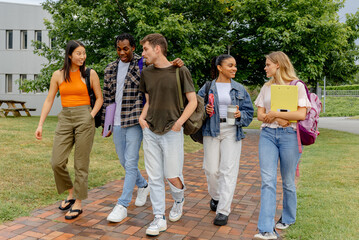 Multiracial group of generation z boys and girls walking together outside the university or high school campus