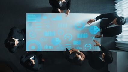 Top down aerial of collaborate professional diverse business people discuss marketing strategy with hologram of marketing data analysis graph, diagram or financial profit investment plan. Directorate.