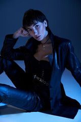 Young woman in black leather pants strikes a dynamic pose on the floor.