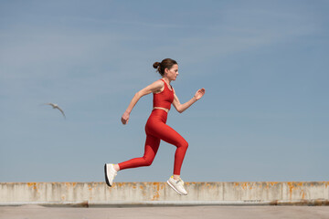 mid adult woman running and jogging outside, blue sky background