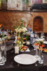 A served banquet table with a bouquet of flowers and a black tablecloth. catering for holidays.