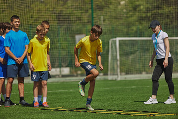 Dynamic Soccer Drill. Young soccer players, boys in uniform training outdoors with coach, doing exercises with agility ladder. Concept of sport, school, childhood, hobby, active lifestyle