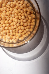 chickpea soaked in water in a glass bowl on marble table.