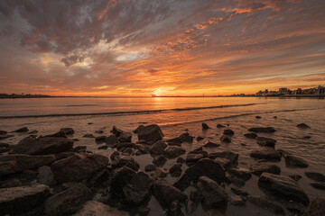Sunset on the beach with rocks and stones visible
