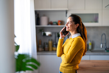 Smiling female entrepreneur discussing over mobile phone while at kitchen counter.