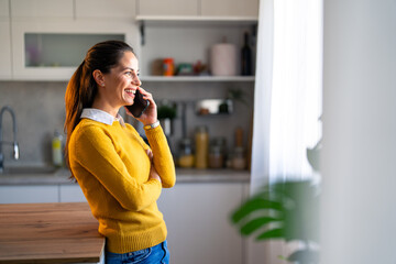 Female business manager sharing ideas over phone call at home while looking through the window