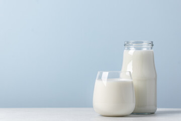 Milk in a glass and bottle blue background with copy space