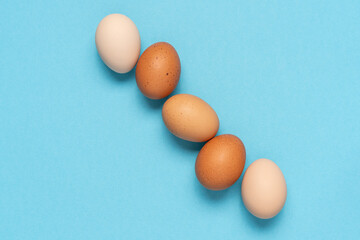 Multi-colored farm eggs neatly stacked on blue background