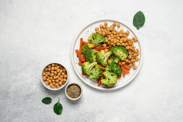 Healthy food broccoli, carrots and chickpeas on a plate top view on a white background with copy space