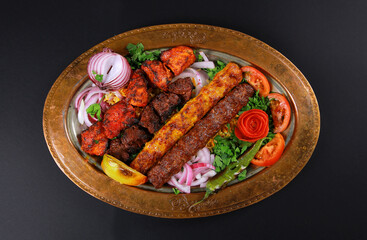 platter with mixed kebab grilled meat vegetable on brass plate black background 