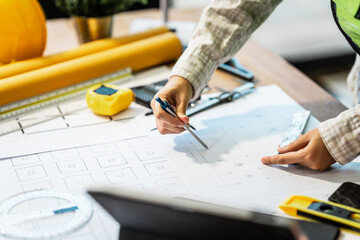 Female architect engineer is drafting blueprints using CAD software, focusing on sustainable infrastructure, renewable energy solutions, and adhering to building codes