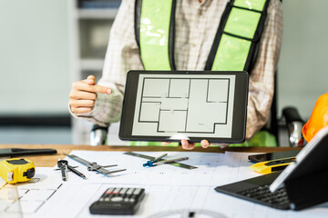 Female architect engineer is drafting blueprints using CAD software, focusing on sustainable...